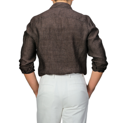 Back view of a person wearing Stenströms' Dark Brown Linen Cutaway Slimline Shirt and white pants, with arms resting on hips—a true summer essential.