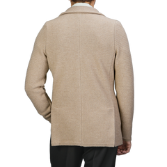 A person is shown from the back against a neutral background, wearing the Beige Merino Wool Knitted Blazer by Stenströms paired with black pants.