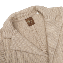 Close-up of the Beige Merino Wool Knitted Blazer from Stenströms, showcasing its textured design with a collar and tailored waist. It features an inside label that reads "Seawool," perfectly combining the elegance of a knitted blazer with the luxurious touch of merino wool.