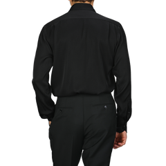 A person is styled in a sophisticated Black Silk Fitted Body Shirt, reminiscent of an elegant piece from Stenströms' collection, facing away from the camera.