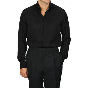 A person dressed in the Stenströms Black Silk Fitted Body Shirt and matching black pants, with one hand in a pocket.