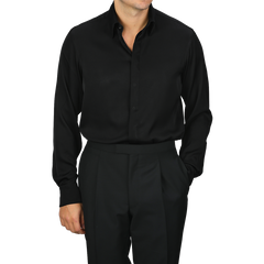 A person dressed in the Stenströms Black Silk Fitted Body Shirt and matching black pants, with one hand in a pocket.