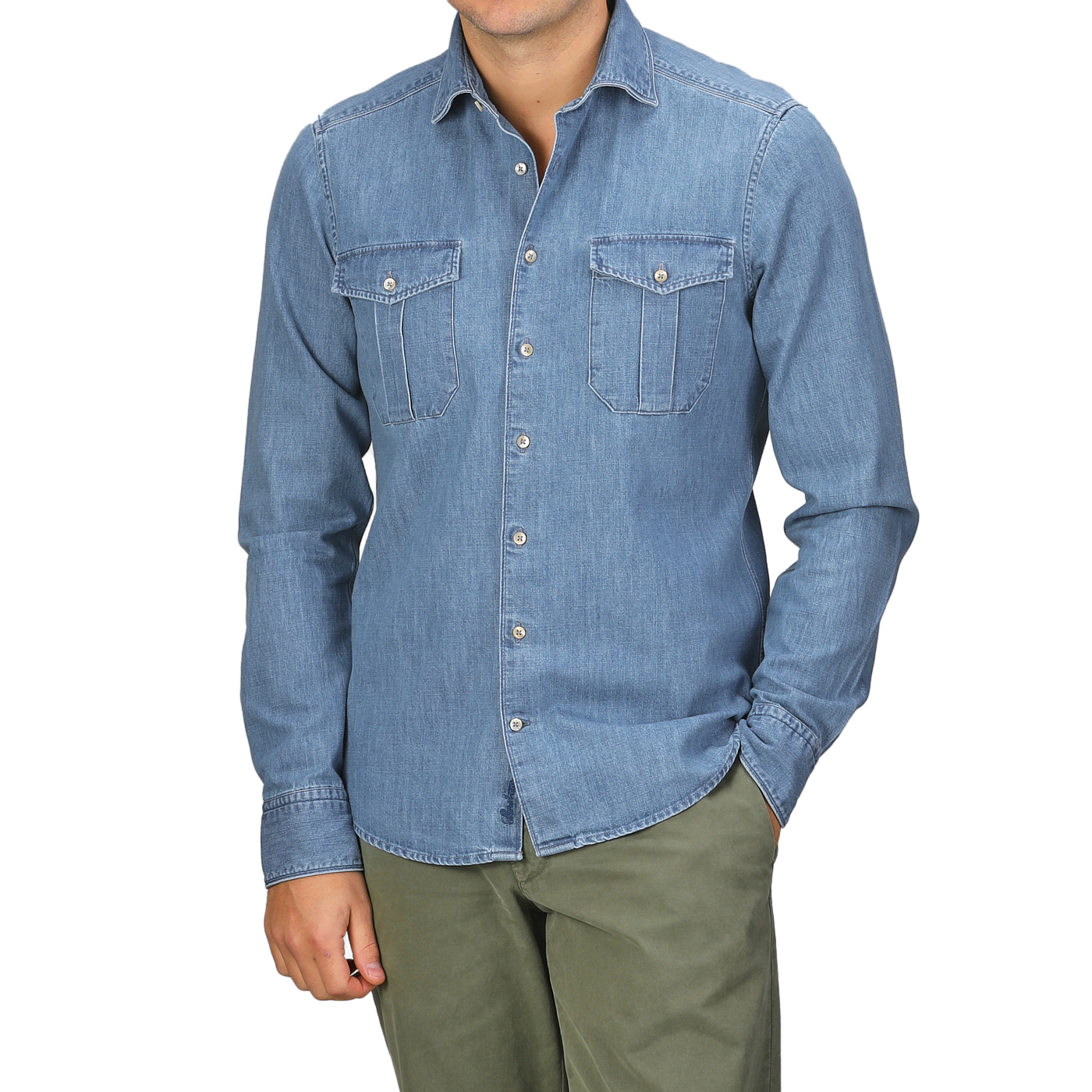 A person stands with one hand in a pocket, wearing the Stenströms Blue Washed Cotton Denim Slimline Shirt featuring two chest pockets and olive green pants.