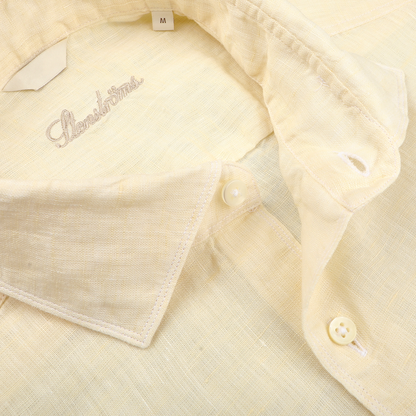 Close-up of a Stenströms Butter Cream Linen Cutaway Fitted Body Shirt, a summer essential, featuring an open collar and two visible buttons.