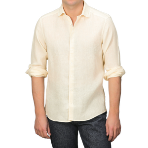 A person wears a Stenströms Butter Cream Linen Cutaway Fitted Body Shirt, ideal for summer, with rolled-up sleeves, paired with dark jeans.