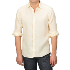 A person wears a Stenströms Butter Cream Linen Cutaway Fitted Body Shirt, ideal for summer, with rolled-up sleeves, paired with dark jeans.