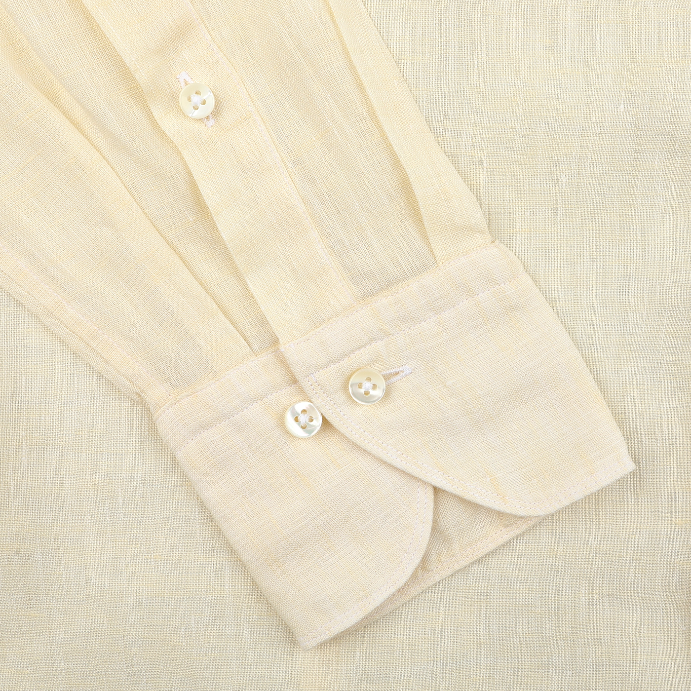 Close-up of a Stenströms Butter Cream Linen Cutaway Slimline Shirt cuff, with buttoned closure on a light fabric background, showcasing this summer essential that's perfect for staying cool and stylish.