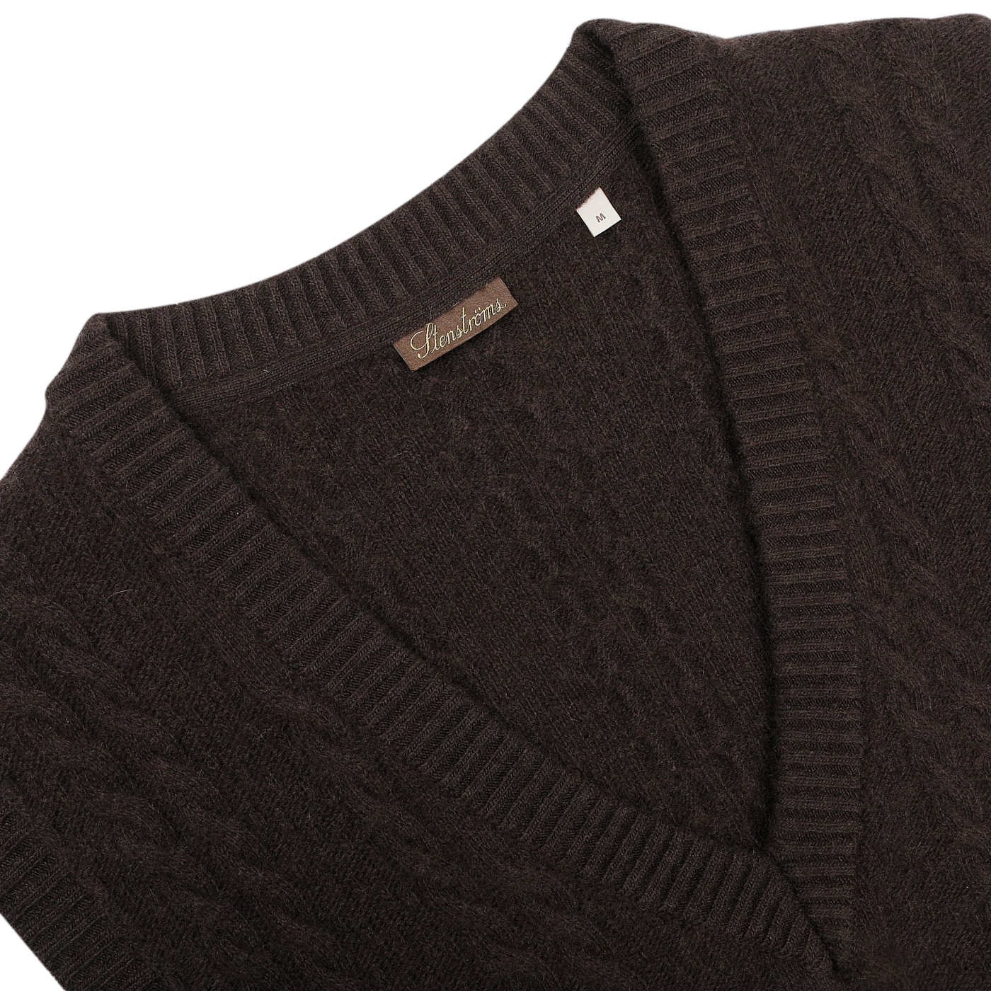 This dark brown cable knit merino slipover from Stenströms, featuring a label on the collar, is a perfect addition to any capsule collection.