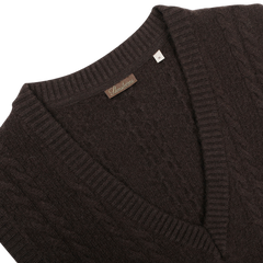 This dark brown cable knit merino slipover from Stenströms, featuring a label on the collar, is a perfect addition to any capsule collection.