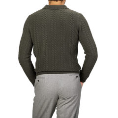 Wearing the Dark Green Merino Cable Knit LS Polo from Stenströms, paired with gray pants and captured from behind, a person exudes the effortless elegance of a capsule collection.