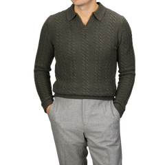 A person wearing a Dark Green Merino Cable Knit LS Polo by Stenströms from the capsule collection and gray pants, with hands in pockets.