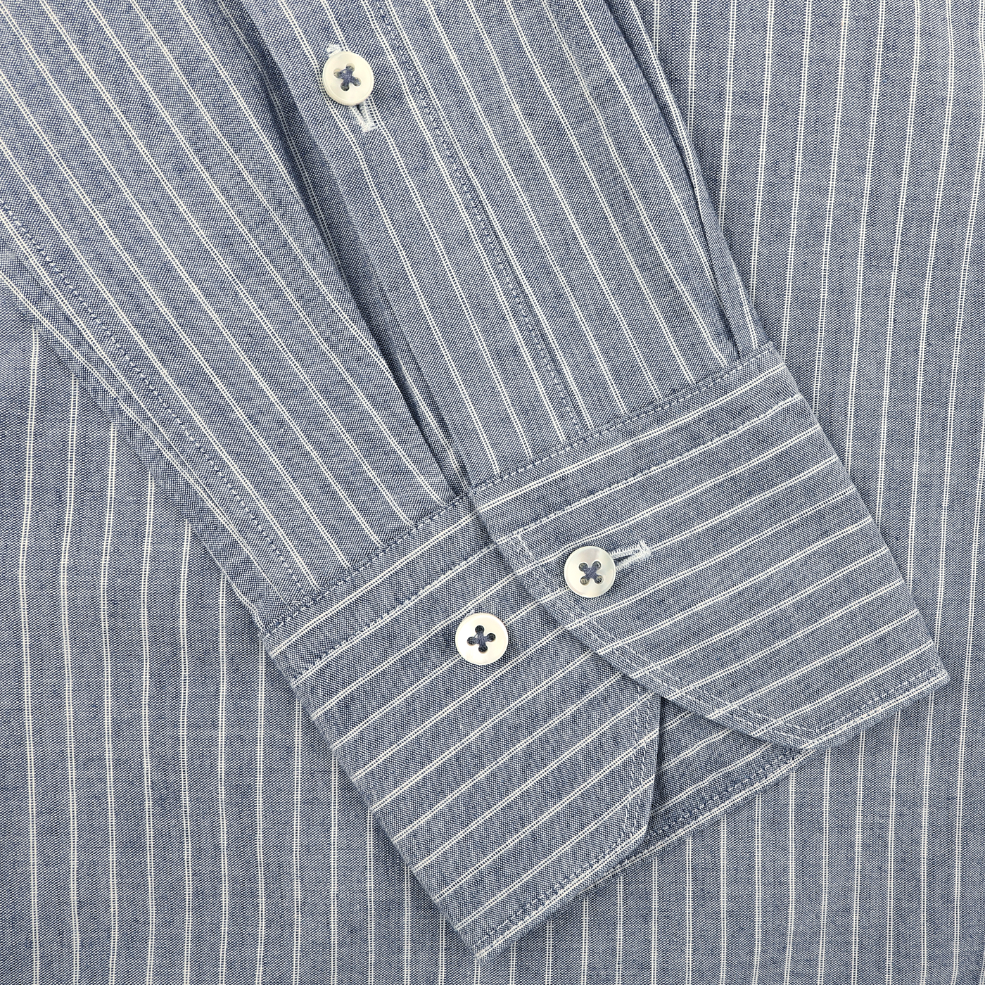 Close-up of the Dark Indigo Striped Washed Cotton Slimline Shirt by Stenströms, showcasing a cut-away collar and white buttons, with elegantly folded sleeves.