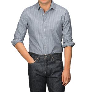 A person wearing a Stenströms Dark Indigo Striped Washed Cotton Slimline Shirt with a cut-away collar and dark jeans stands with one hand in a pocket.