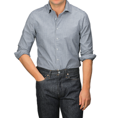 A person wearing a Stenströms Dark Indigo Striped Washed Cotton Slimline Shirt with a cut-away collar and dark jeans stands with one hand in a pocket.