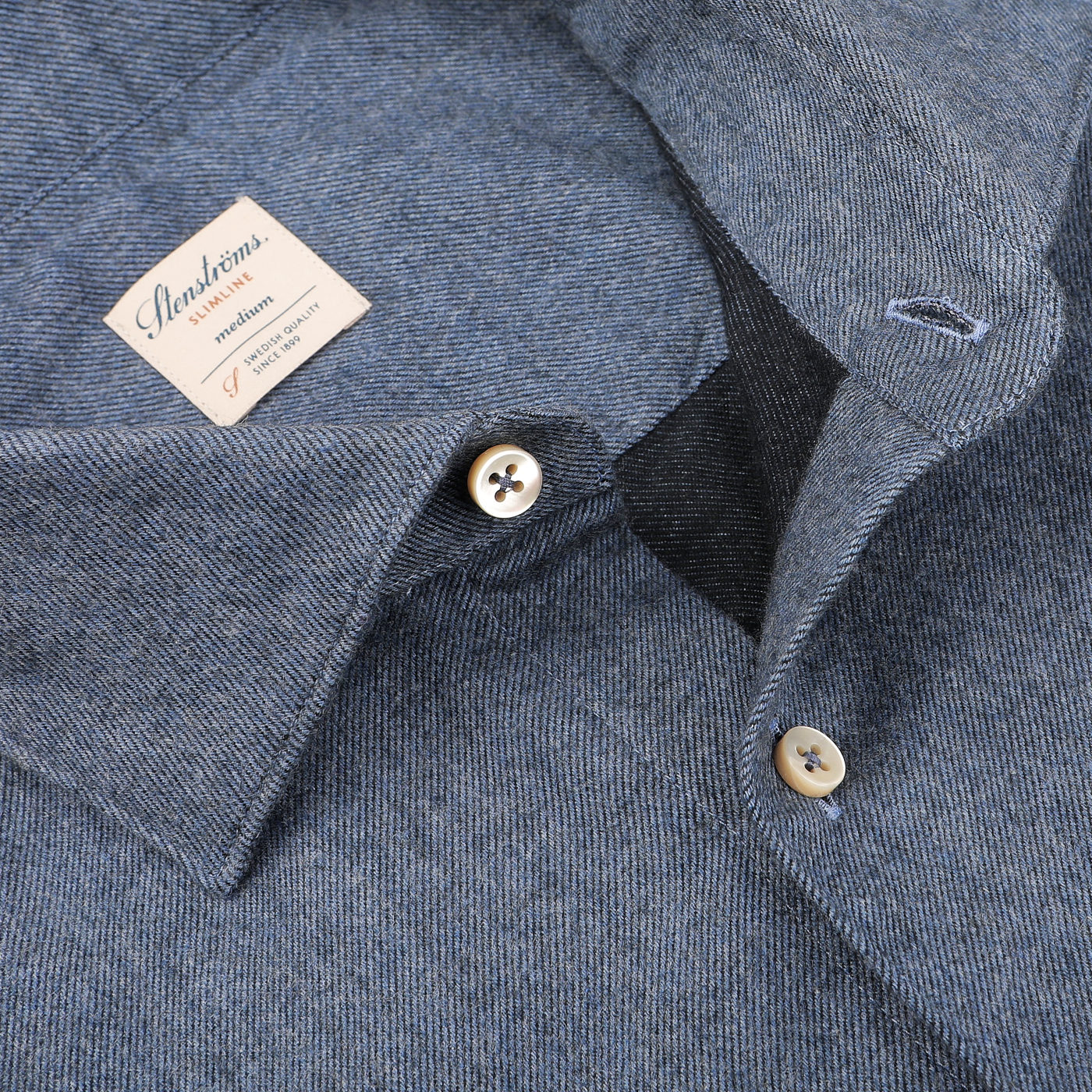 Close-up of a Denim Blue Cotton Flannel Cut-Away Slimline Shirt by Stenströms, featuring gray stripes, brown buttons, and a visible tag labeled "Stenströms," crafted from soft brushed cotton twill.