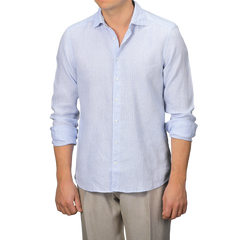 A man stands against a plain background effortlessly embracing summer style, wearing Stenströms' Light Blue Micro-Checked Linen Fitted Body Shirt with rolled-up sleeves and light-colored trousers.