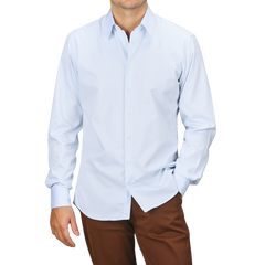 A person wearing the Stenströms Light Blue Cotton Twill Fitted Body Shirt paired with brown pants poses with one hand in the pocket against a plain background.