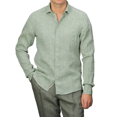 Someone in a Stenströms Light Green Linen Cutaway Fitted Body Shirt and gray pants stands against a neutral background, with the shirt untucked.