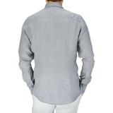 Rear view of a person wearing a Stenströms Light Grey Linen Fitted Body Shirt with cutaway collar and white pants.
