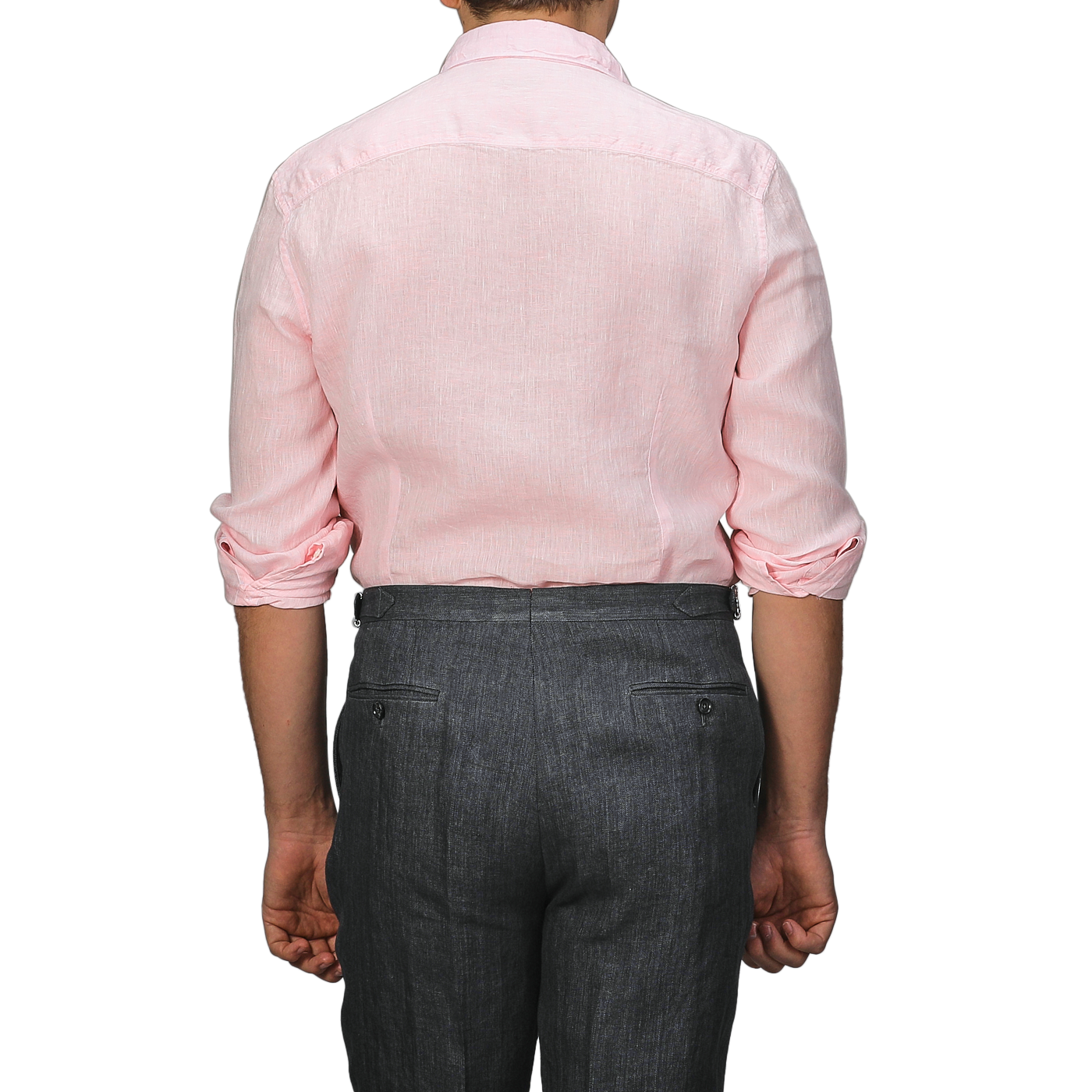 Viewed from the back, a person wears Stenströms' Light Pink Linen Cutaway Slimline Shirt with rolled-up sleeves and dark gray pants, showcasing a summer essential.