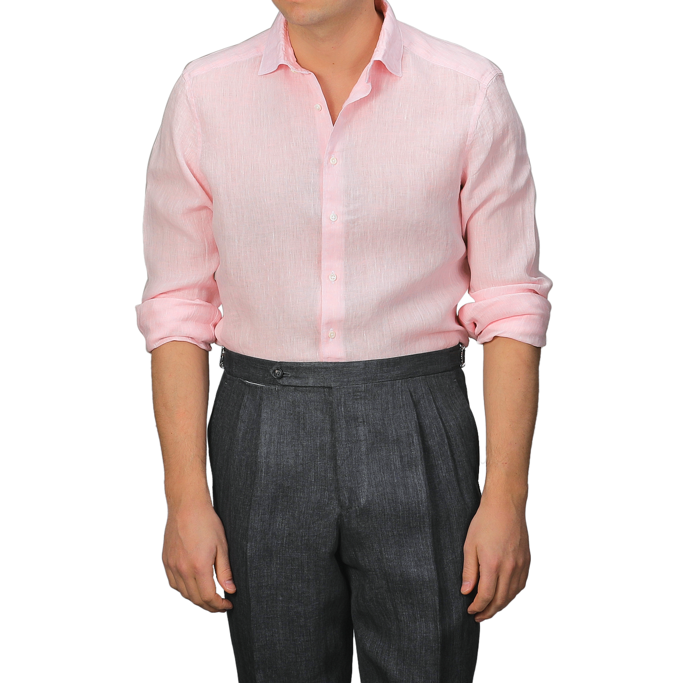 A person wears a Stenströms Light Pink Linen Cutaway Slimline Shirt with rolled-up sleeves, paired with dark gray pleated trousers. This summer essential's Slimline cut ensures a sleek and stylish look.