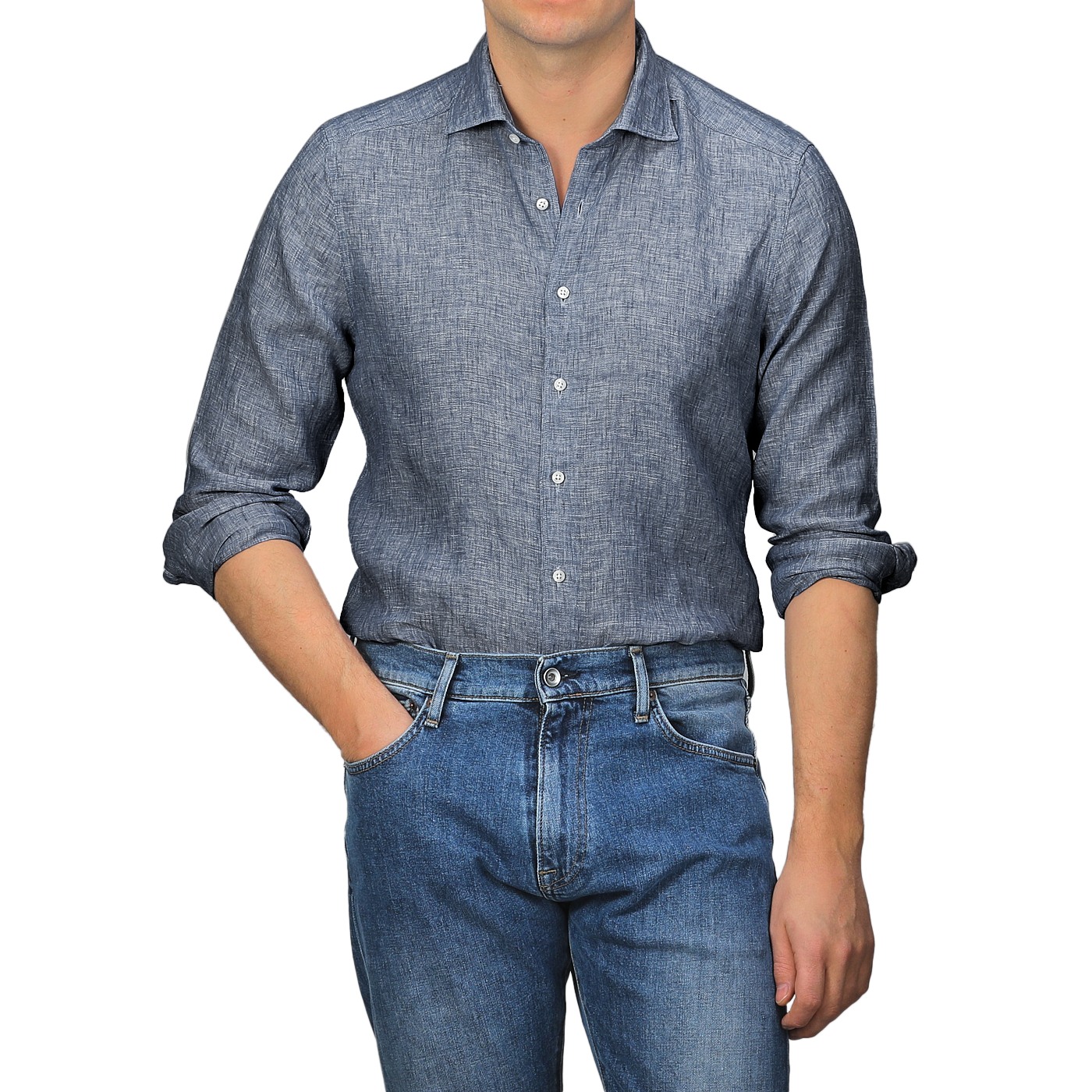 A person embodies the perfect summer look by wearing a Stenströms Mid Blue Linen Cutaway Slimline Shirt with rolled-up sleeves and blue jeans, standing with one hand in the pocket.