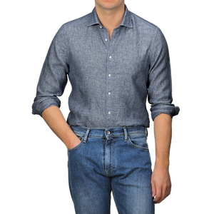 A person embodies the perfect summer look by wearing a Stenströms Mid Blue Linen Cutaway Slimline Shirt with rolled-up sleeves and blue jeans, standing with one hand in the pocket.