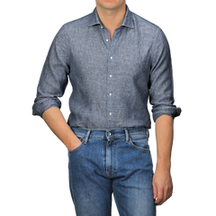 A person embodies the perfect summer look by wearing a Stenströms Mid Blue Linen Cutaway Slimline Shirt with rolled-up sleeves and blue jeans, standing with one hand in the pocket.