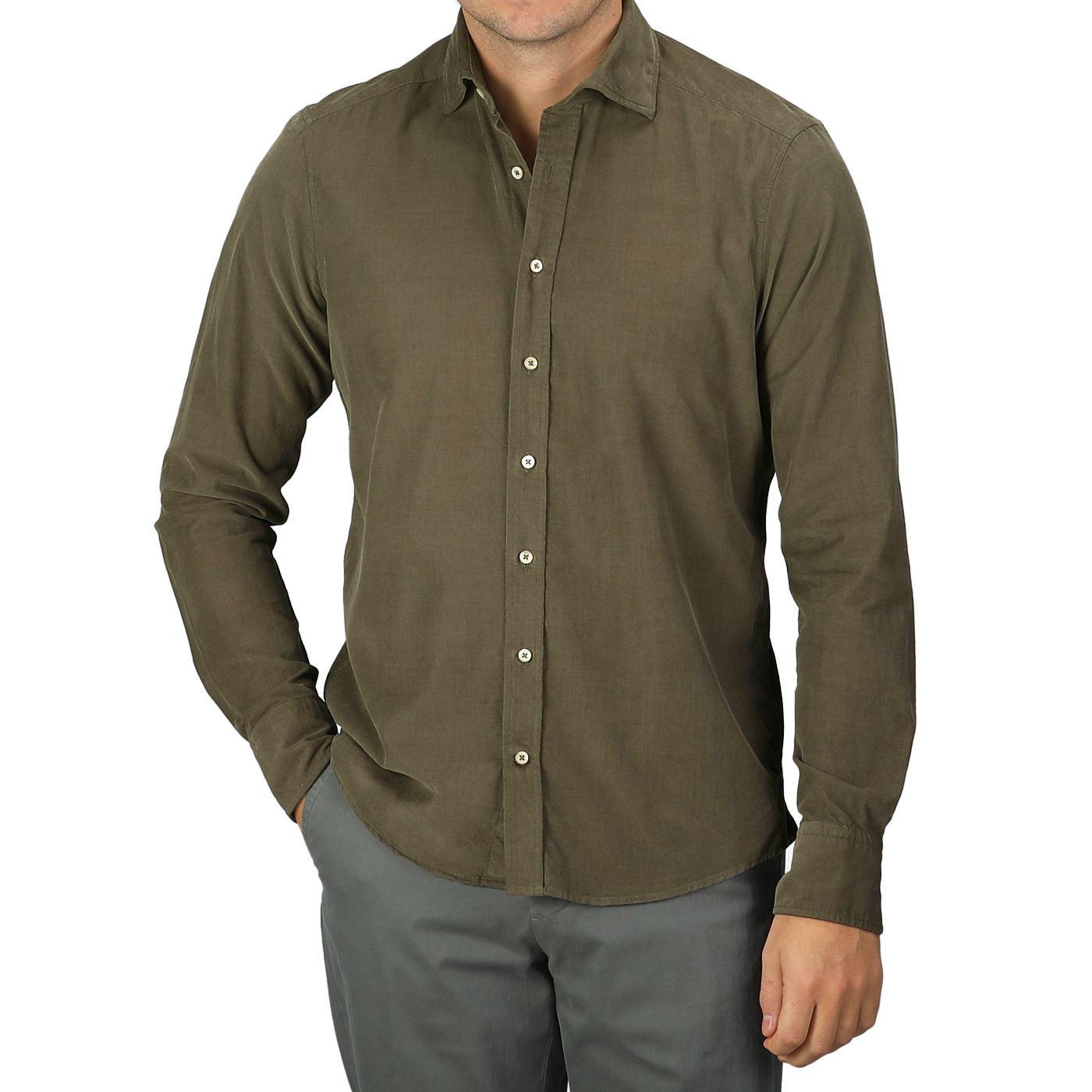 A man in a slimline cut, moss green shirt and gray pants stands with one hand in his pocket against a neutral background. The Stenströms Moss Green Cotton Corduroy Slimline Shirt adds a touch of elegance to his relaxed pose.