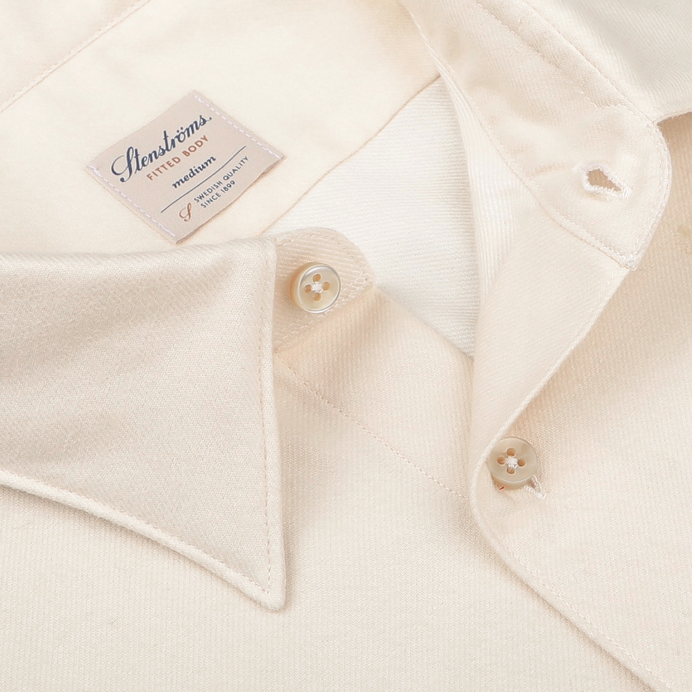 Close-up of the Off-White Cotton Flannel Fitted Body Shirt by Stenströms, featuring a label inside the collar. Its fitted cut and elegant mother-of-pearl buttons are beautifully displayed against the textured fabric.