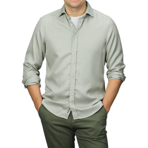 A person stands with hands in pockets, wearing a Stenströms Pale Green Lyocell Slimline Shirt and dark gray pants.