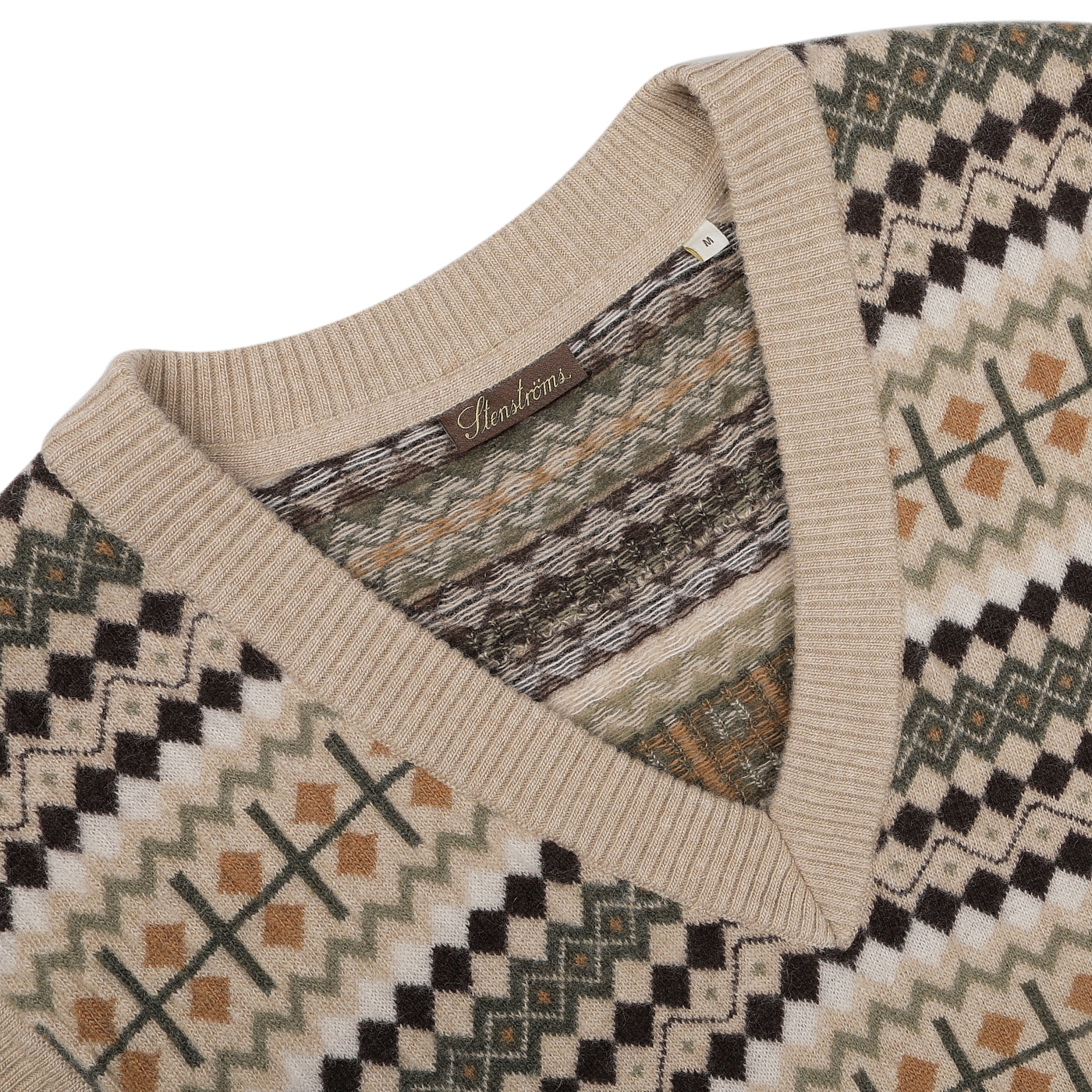 Close-up of the Stenströms Taupe Beige Merino Wool Patterned Slipover, showcasing its V-neck design crafted from soft merino wool, with a geometric pattern in beige, black, green, and brown tones. Part of our exclusive capsule collection.