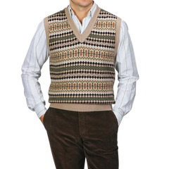 A person is standing against a gray background, wearing a Stenströms Taupe Beige Merino Wool Patterned Slipover over a striped shirt, paired with brown corduroy pants.