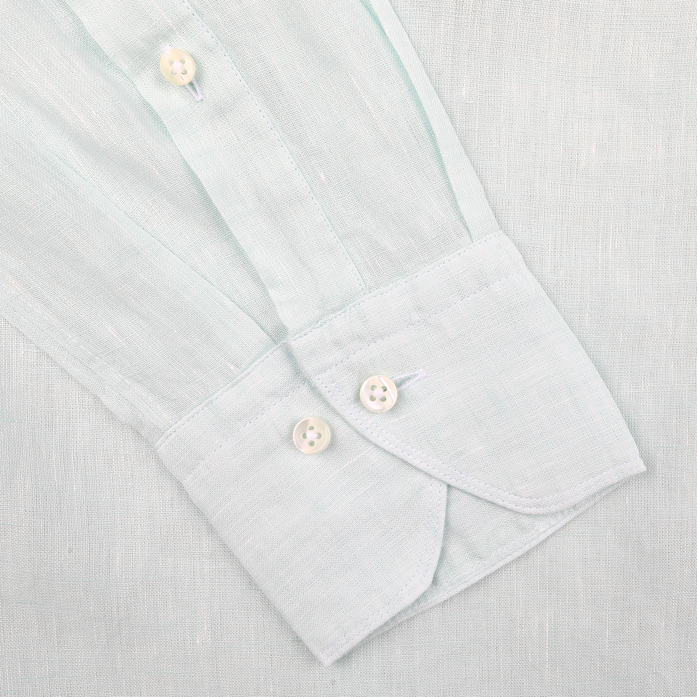 Close-up of Stenströms' Turquoise Linen Cutaway Slimline Shirt cuff with two white buttons on a matching fabric, highlighting its summer essential charm.