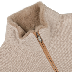 A close-up of the Light Beige Cashmere Fur Collar Cardigan from Stile Latino highlights its resemblance to a cashmere cardigan. The cozy, textured collar and partially unzipped zipper reveal the soft lining inside. The fabric showcases a ribbed and woven pattern, reflecting the elegance typical of luxury brands like Stile Latino.