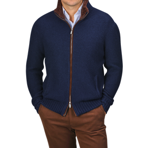 A person is dressed in a Royal Blue Cashmere Fur Collar Cardigan from Stile Latino, worn over a blue collared shirt and brown pants. This cardigan showcases cashmere fibers with a distinguished brown fur collar, radiating refined elegance.