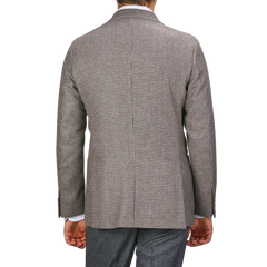 A person is pictured from behind against a plain background, wearing Studio 73's Brown Houndstooth Lambswool Blazer and dark grey pants made from super 110s lambswool.