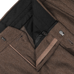 Close-up of the waistband of Studio 73's Brown Melange Wool Flannel Pleated Trousers, showcasing a visible zipper, black button, and clasp fastening. The high-waist design is crafted from pure wool flannel with a black interior lining.