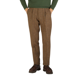 A man wearing Studio 73 Brown Rustic Checked Wool Tweed Pleated Trousers and a green sweater.