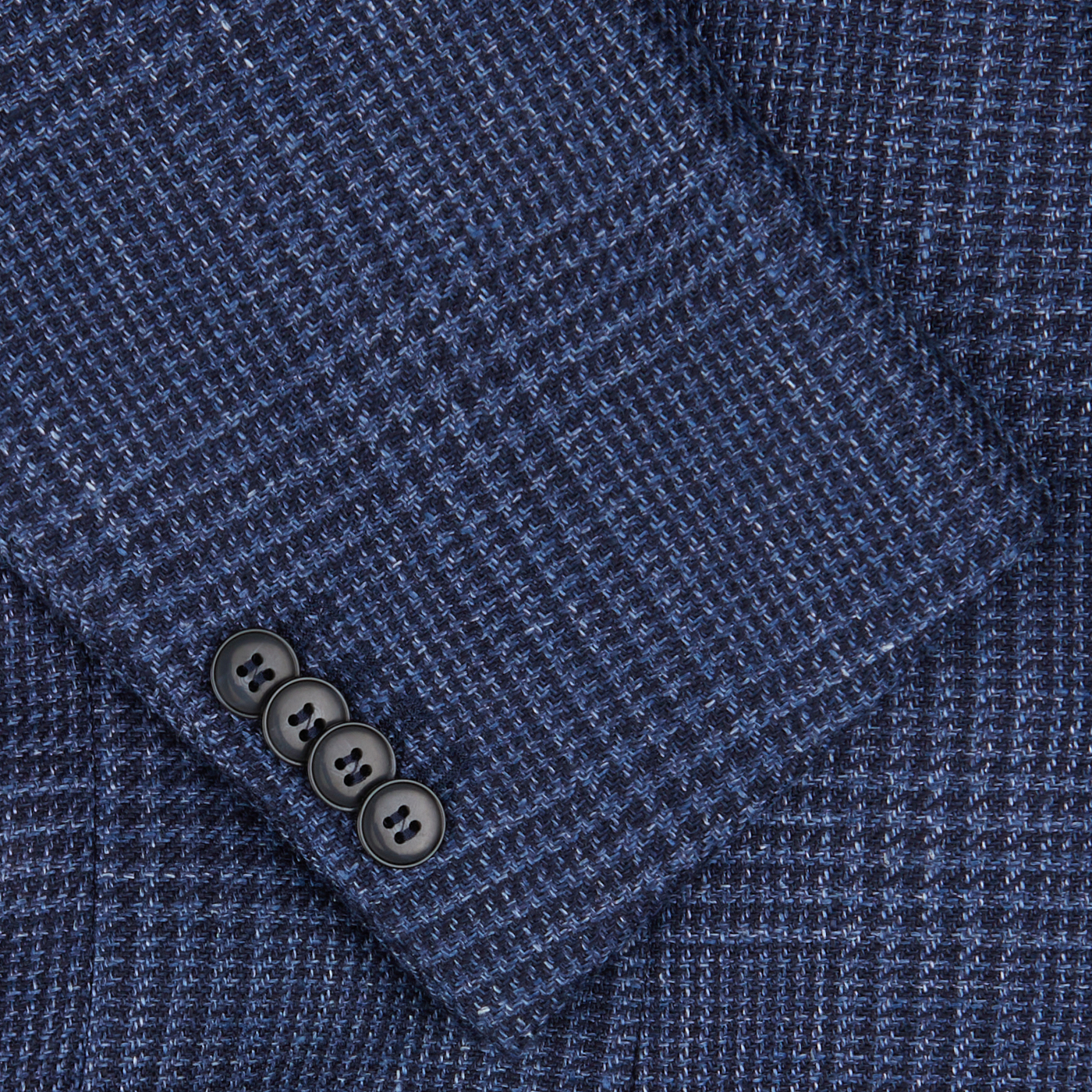 Close-up of a Studio 73 Dark Blue Checked Wool Linen Blazer fabric with a herringbone pattern and a row of buttons.