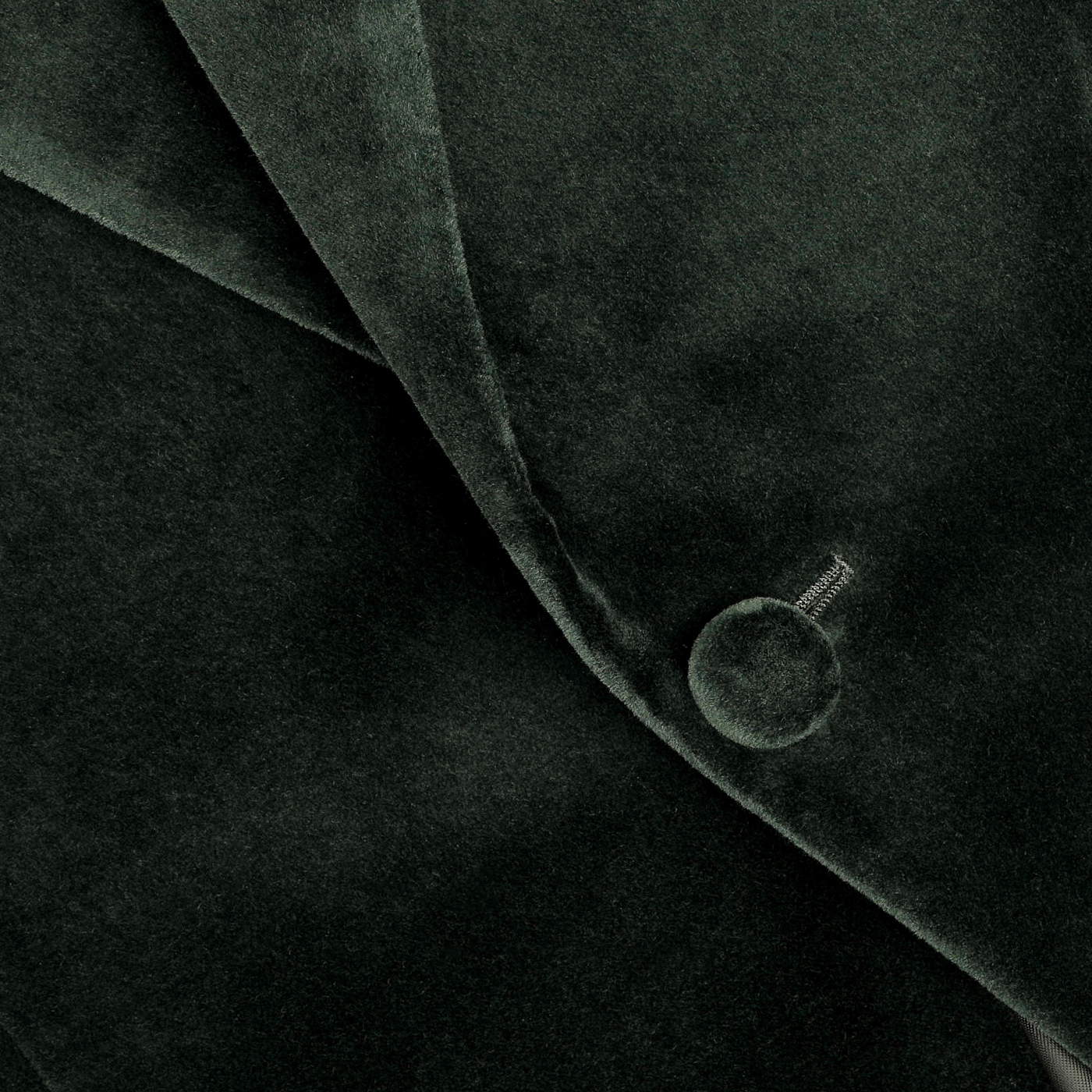 A close-up of the Dark Green Cotton Velvet Dinner Jacket by Studio 73 highlights its luxurious velvet fabric, featuring a button and elegantly folded lapel, making it ideal for formal evening wear.