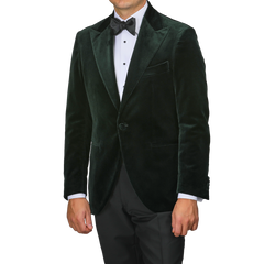 Dressed with sophistication, an individual wears Studio 73's Dark Green Cotton Velvet Dinner Jacket, complemented by a crisp white dress shirt and a black bow tie, ideal for formal evening occasions.