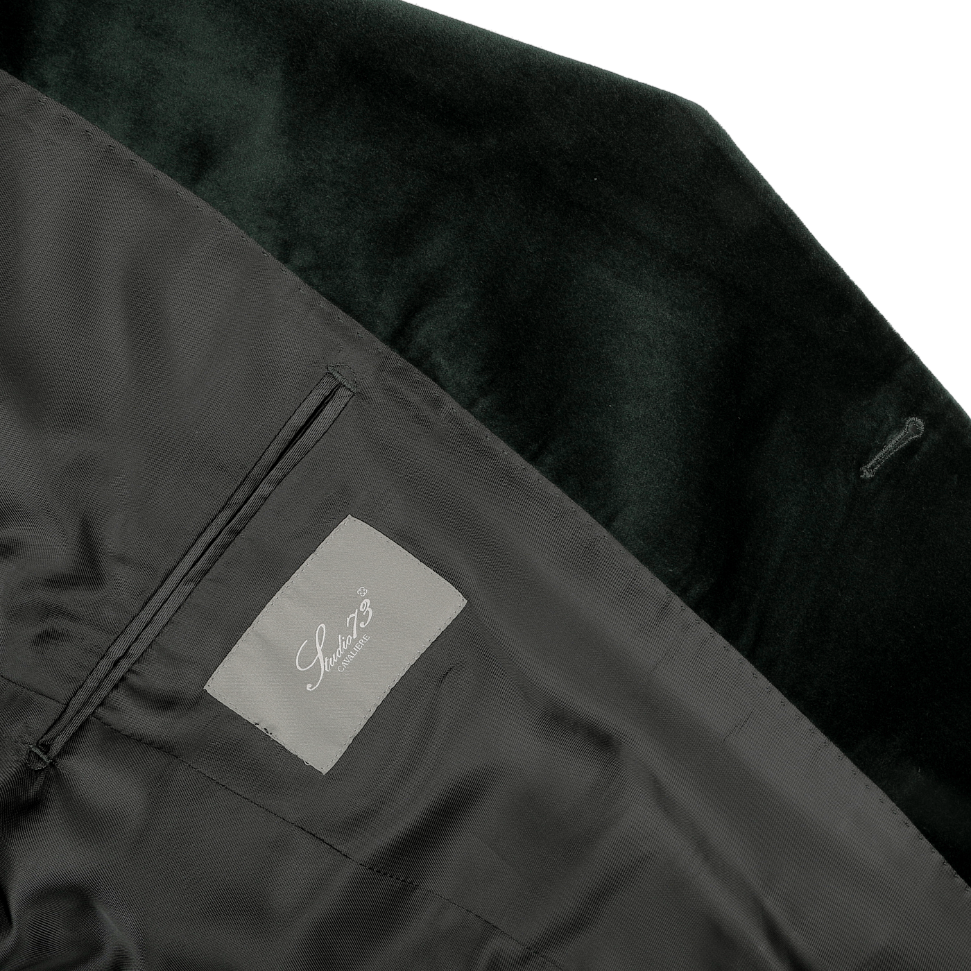 Close-up of a dark green dinner jacket's interior, highlighting the classic "Studio 73" label on the inner pocket, set against a luxurious cotton velvet lining.