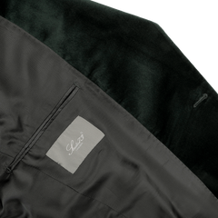 Close-up of a dark green dinner jacket's interior, highlighting the classic "Studio 73" label on the inner pocket, set against a luxurious cotton velvet lining.