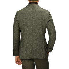 A man wearing a Studio 73 Green Melange Wool Tweed Blazer stands with his back to the camera, his left hand in his pocket.