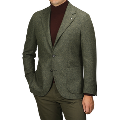 A person wearing the Studio 73 Green Melange Wool Tweed Blazer over a brown turtleneck and olive pants stands against a plain background. The individual is shown from the shoulders down.