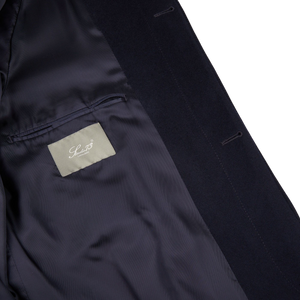 The back of a Navy Wool Cashmere Raglan Coat with a Studio 73 label on it.