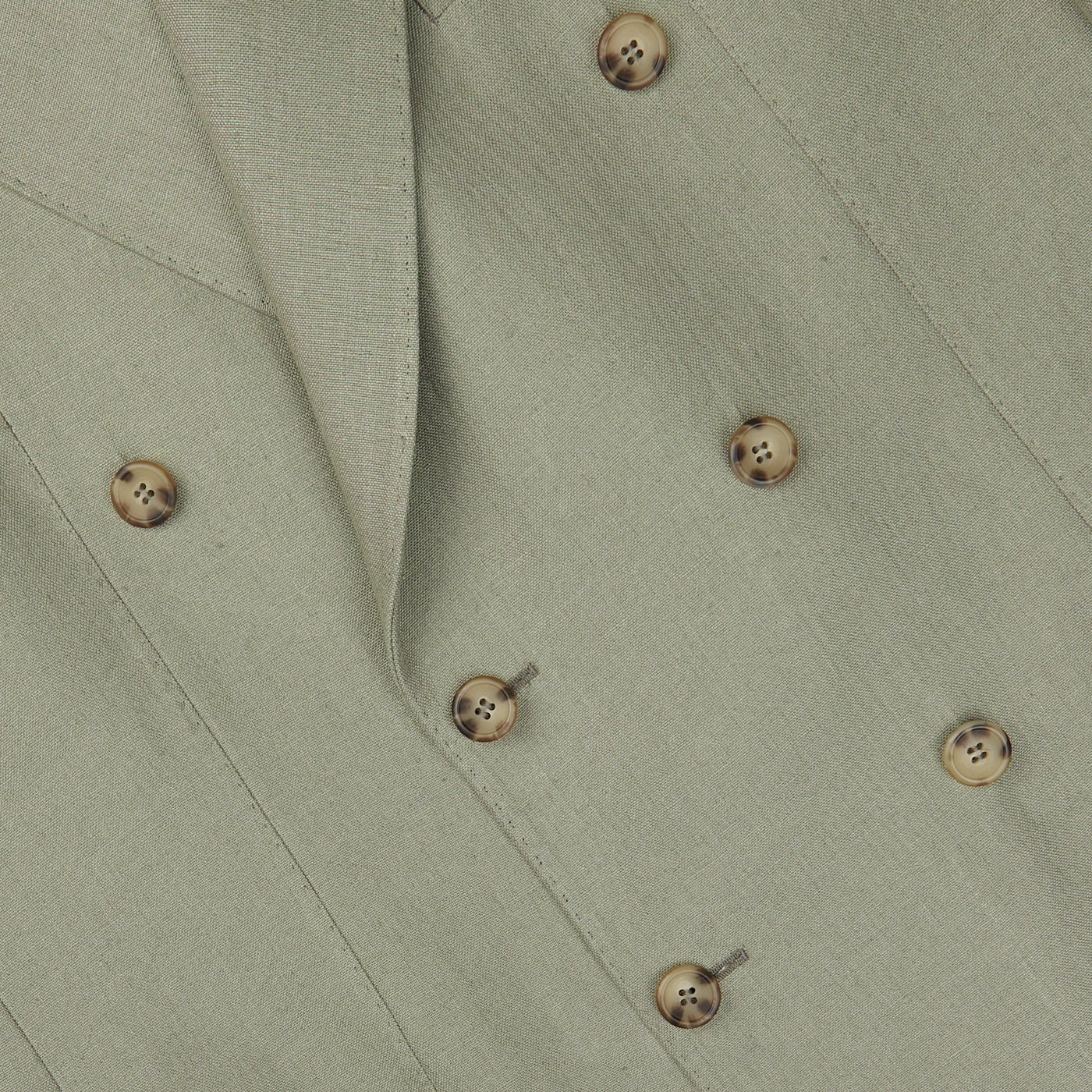 Close-up of a sage green, Studio 73 Sage Green Canapa Hemp DB Suit with tan buttons arranged in two parallel rows. The fabric has a smooth, textured appearance.