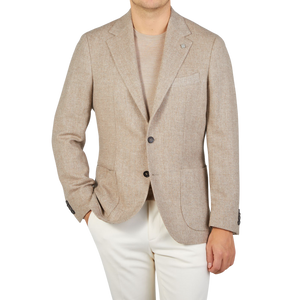 A man wearing a Taupe Beige Wool Herringbone Blazer by Studio 73 and white pants.