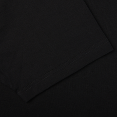 Close-up of the sleeve of a Sunspel Black Classic Cotton T-Shirt against a black background, emphasizing the cotton stitching and fabric texture.